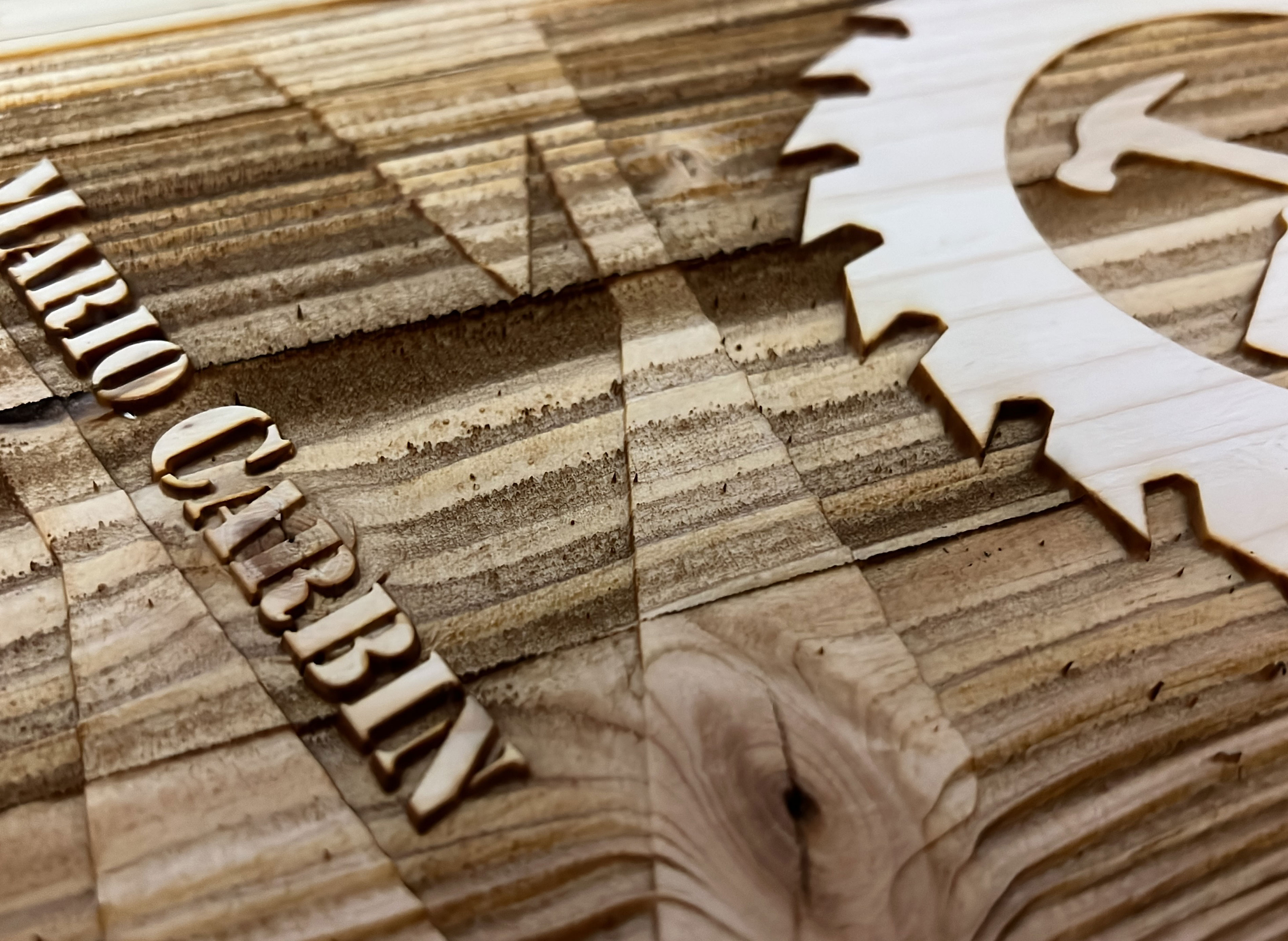 Reliefgraviertes Firmenschild mit Zahnrad als Laserservice-Beispiel.